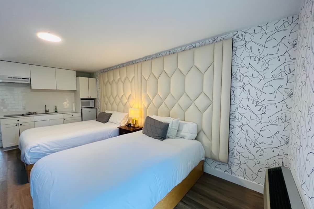 Ett hotellrum med två sängar, ett litet kök och en vägg med ett mönster.