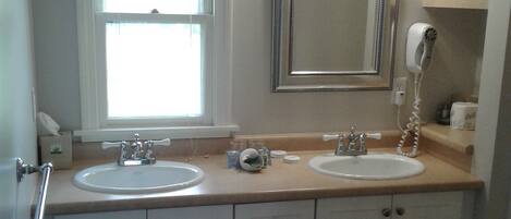 Un baño con dos lavamanos, un espejo y una ventana.