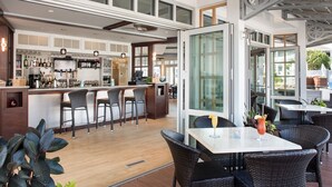 A modern bar area with a counter, bar stools, and a seating area with tables and chairs. - Anchorage by the Sea (Ogunquit)