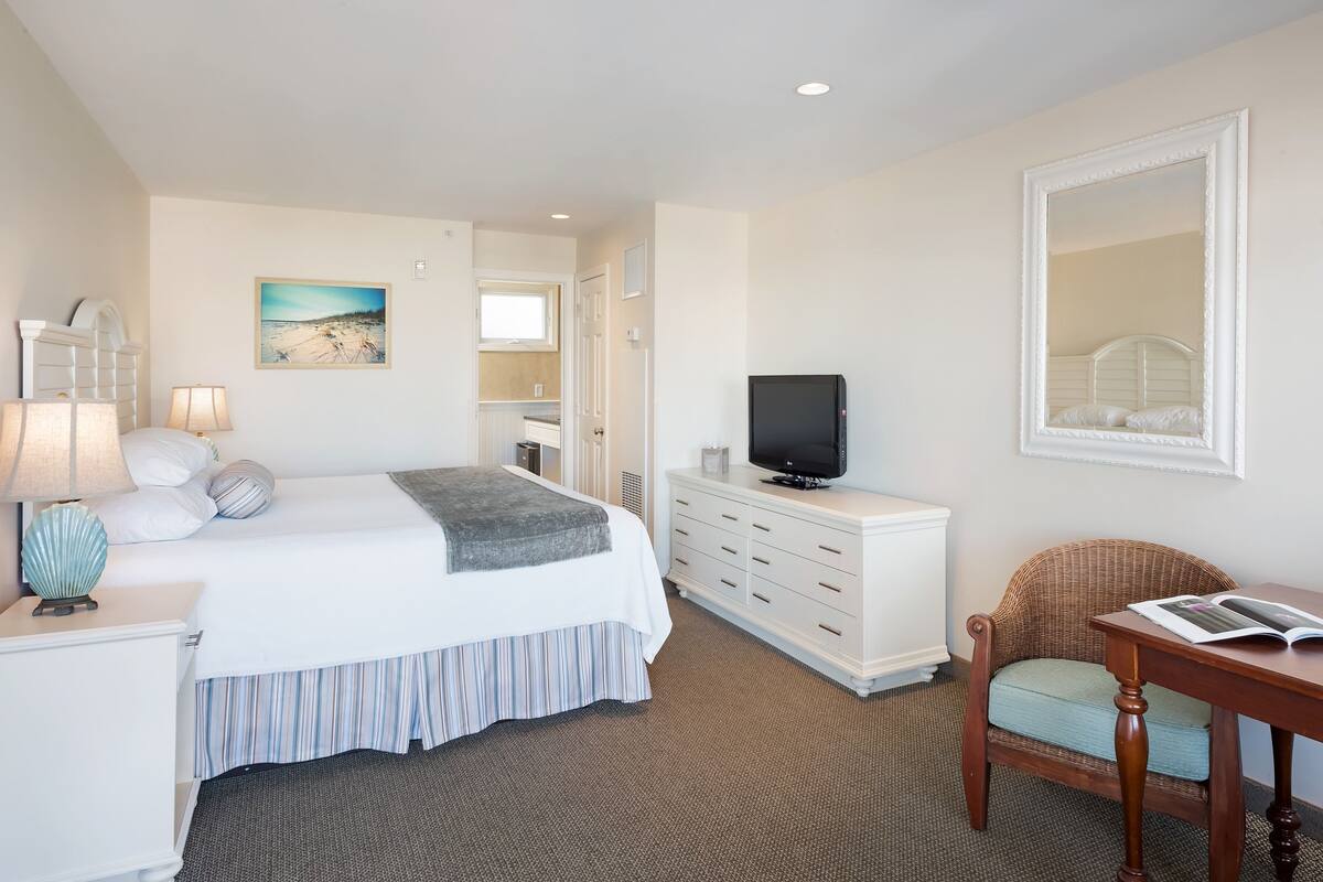 A hotel room with a bed, a television, a desk, and a chair.