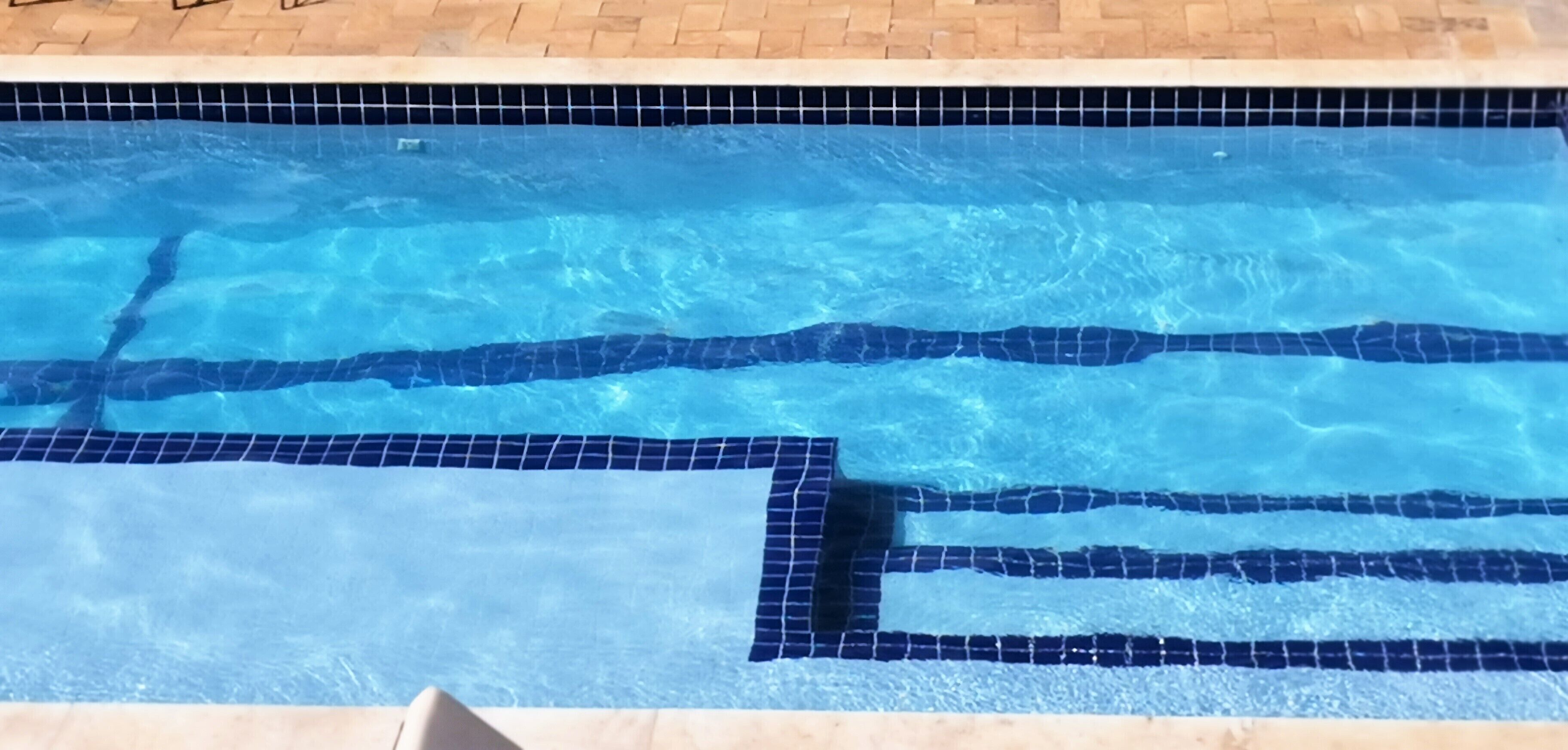 A swimming pool with clear blue water and tiled edges.