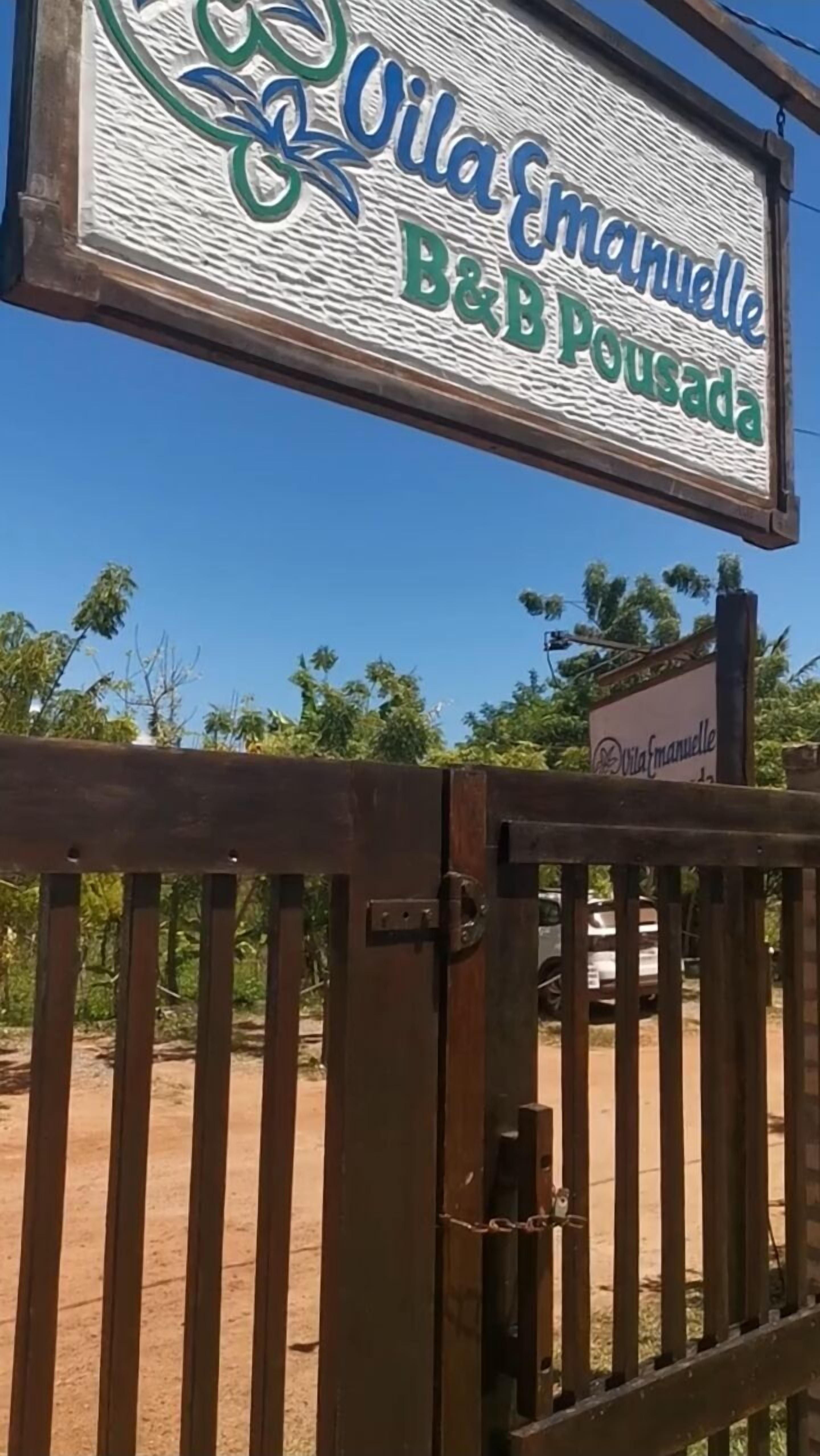 A sign for Vila Emanuel B&B Pousada with a wooden gate in the foreground.