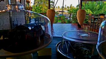 Un restaurant avec vue sur une piscine et des palmiers. De grands pots sont disposés sur les tables.