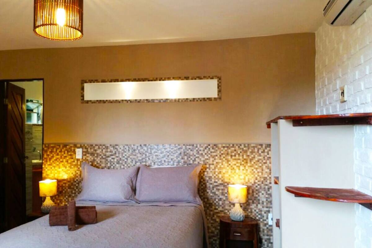 A bedroom with a bed, two bedside lamps, a mirror, and a wooden shelf.