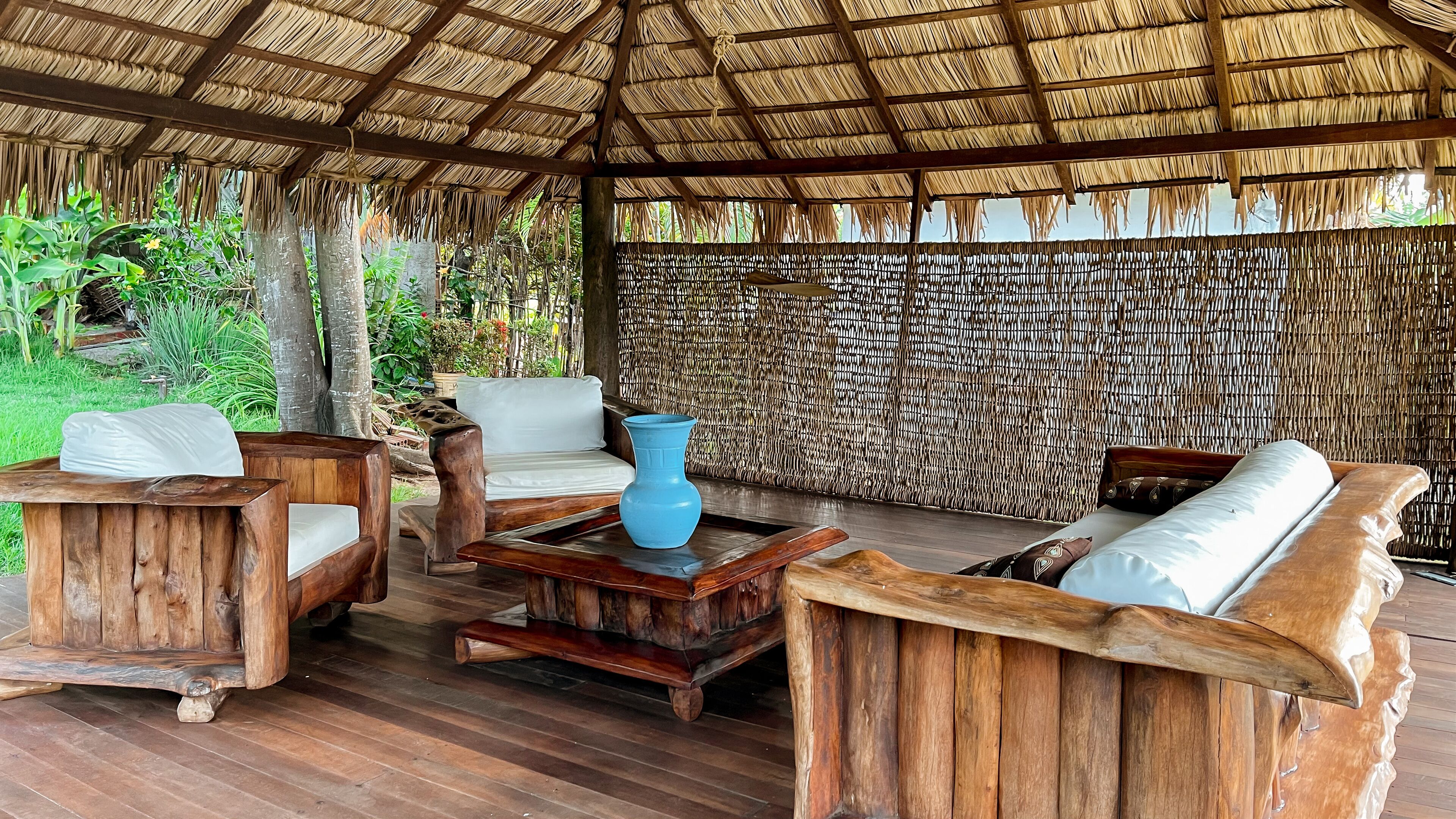 An outdoor seating area with wooden furniture and a thatched roof.