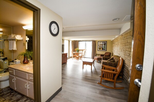 A hotel room with a bathroom, a dining area with a table and chairs, and a living room with a rocking chair. - Fairway Inn and Suites, an Ascend Collection Hotel (Mishicot)