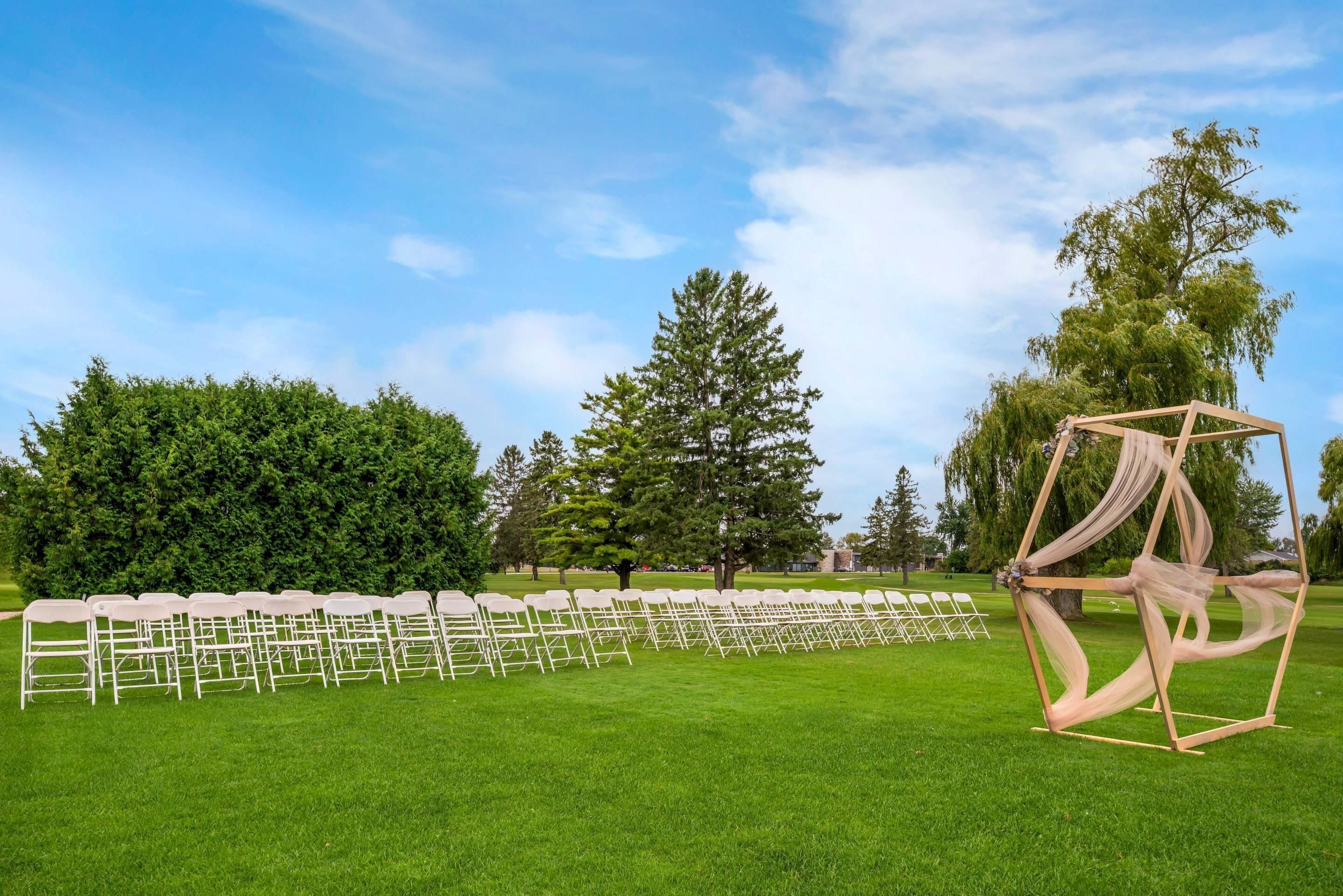 A grassy outdoor area with rows of white chairs arranged for an event.