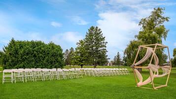 A grassy outdoor area with rows of white chairs arranged for an event.