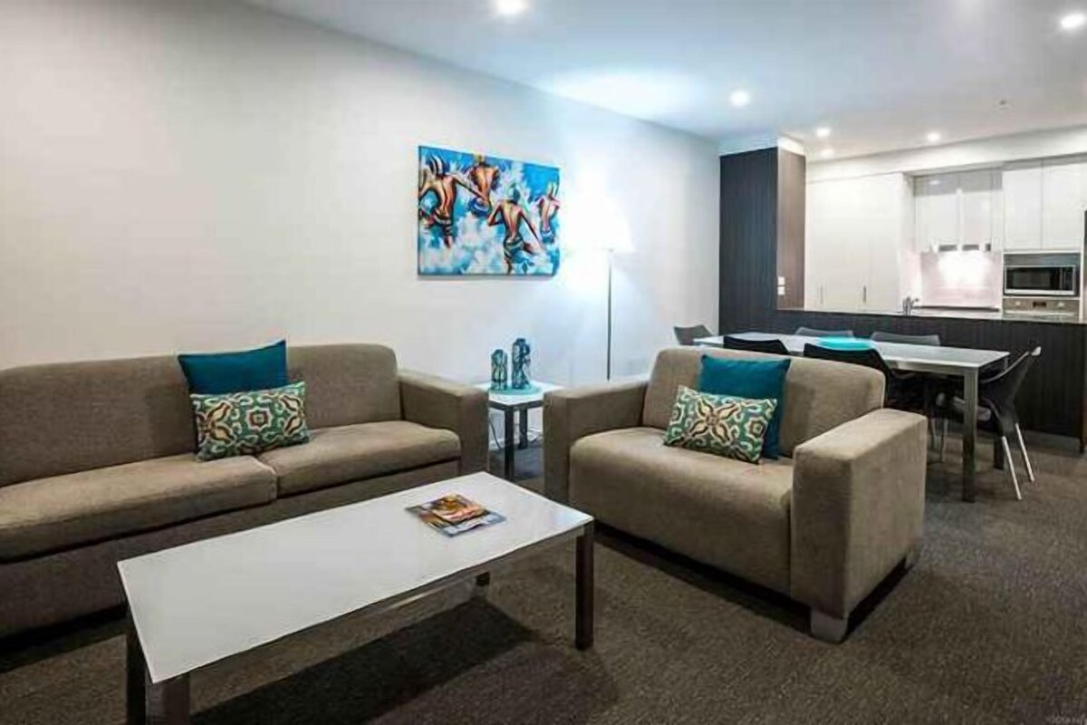 Una sala de estar moderna con dos sofás, una mesa de centro y un comedor con una mesa y sillas.