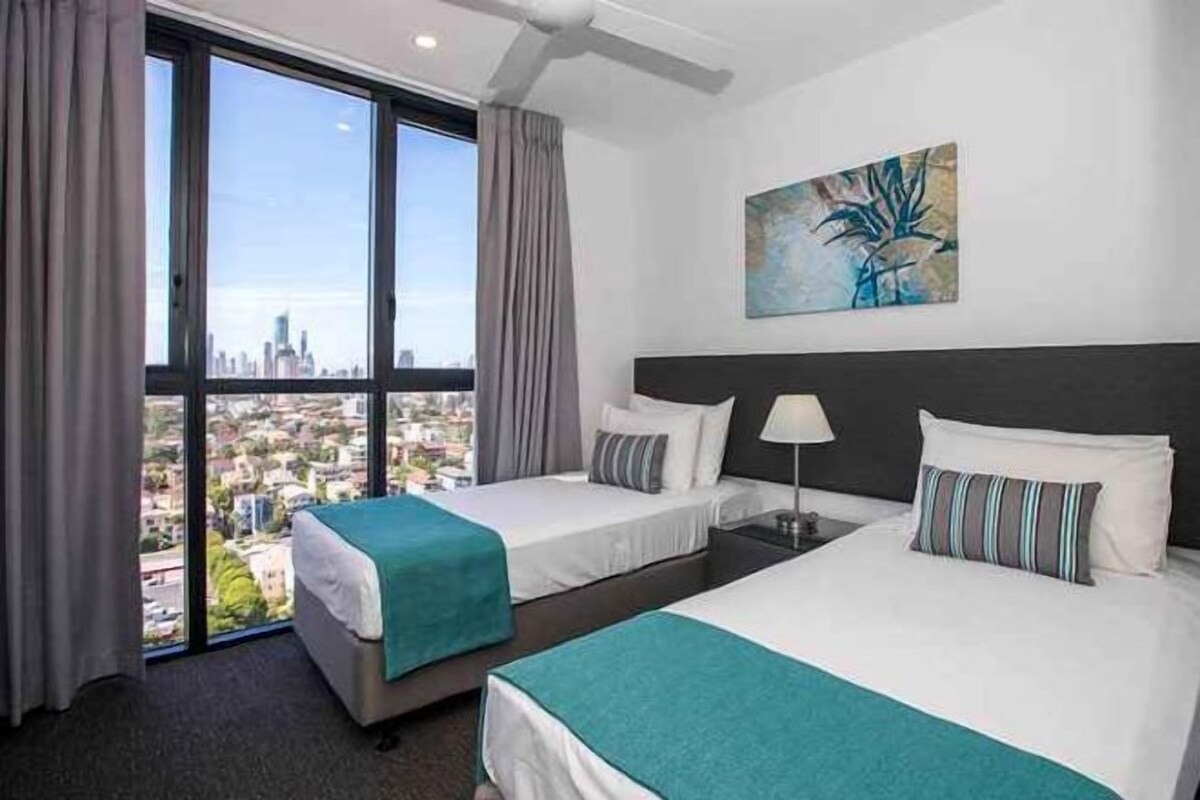Habitación de hotel con dos camas, vista a la ciudad y un cuadro en la pared.