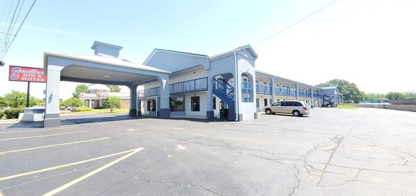 A motel with a blue and white exterior, a gas station, and a parking lot.