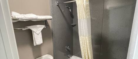 A bathroom with a toilet, a bathtub, a shower curtain, and a towel rack.