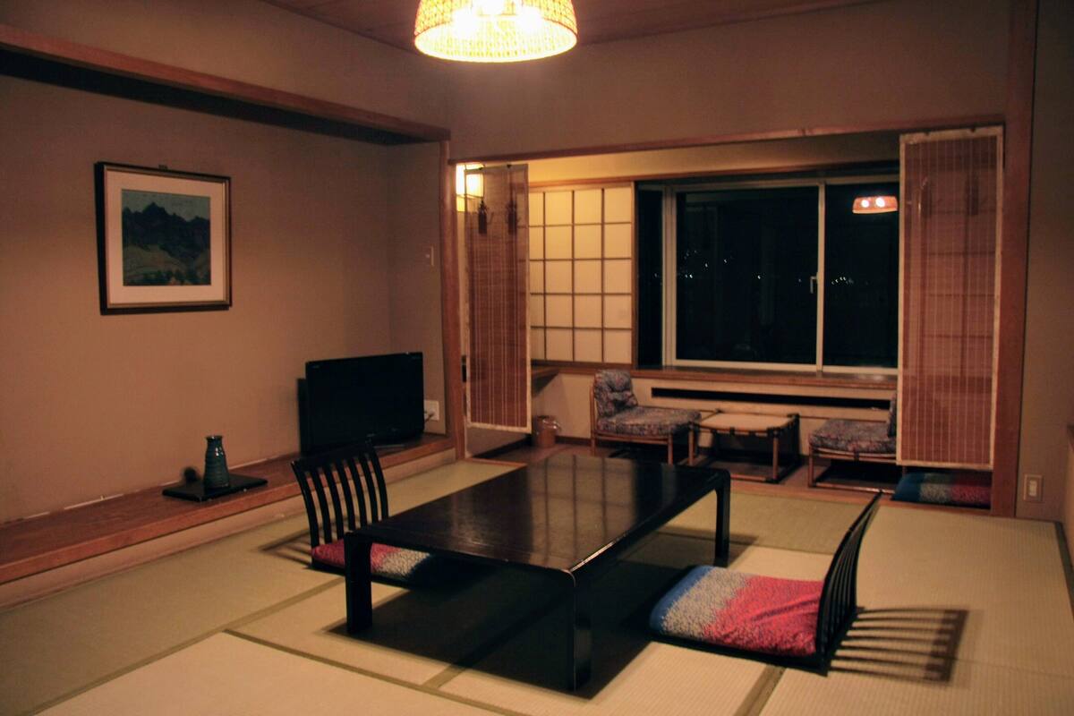 A traditional Japanese-style living room with tatami flooring, a low table, and a television.