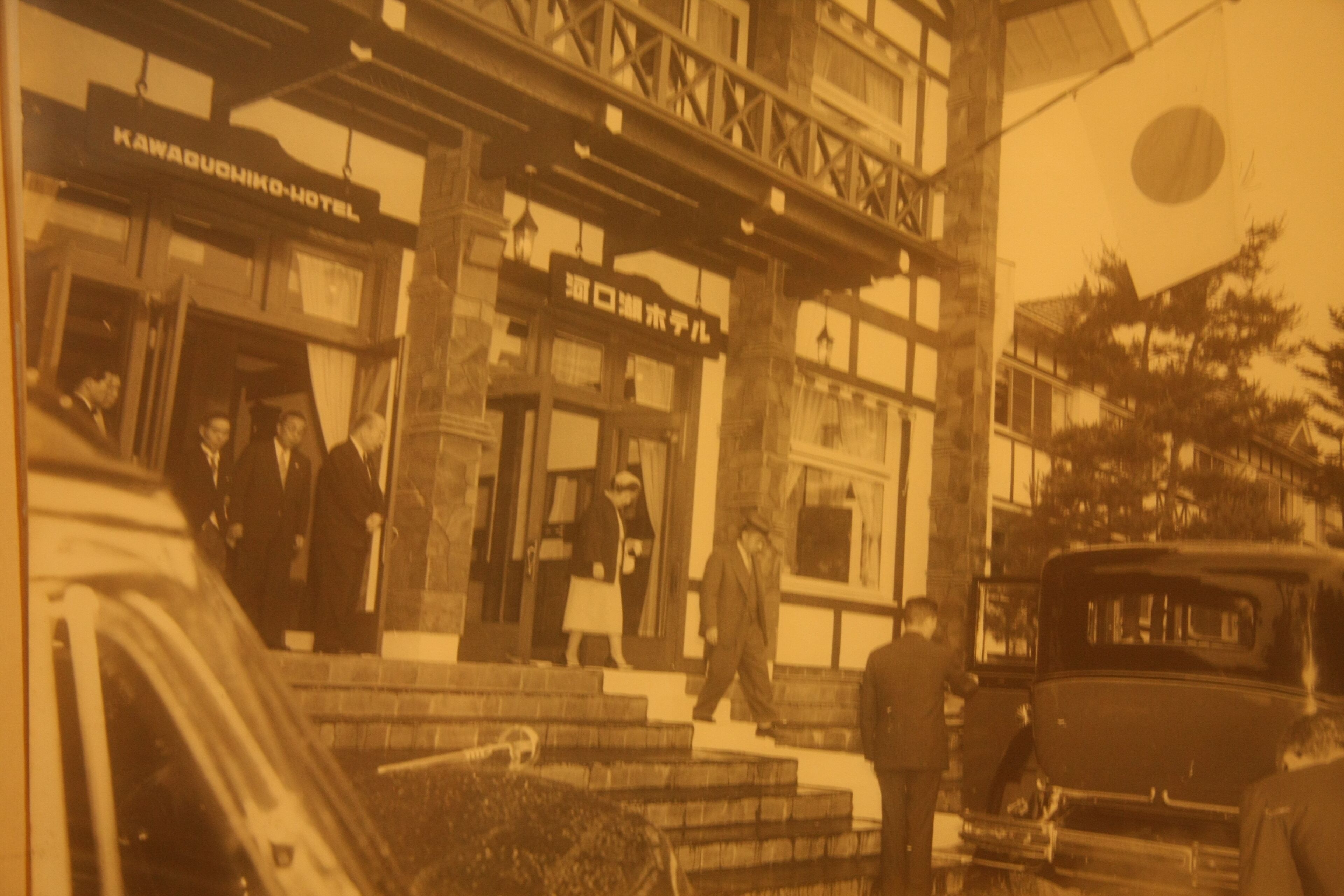A vintage hotel with a sign reading "Kawaduchiko Hotel" and a traditional Japanese architectural style.