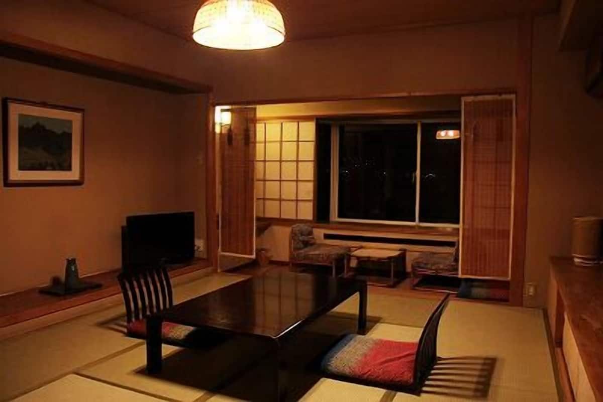 Ein traditioneller japanischer Raum mit Tatami-Bodenbelag, einem niedrigen Tisch und verschiebbaren Shoji-Türen.