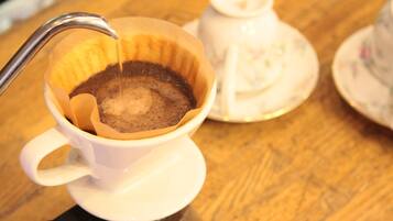 Una taza de café con plato y una cafetera sobre una mesa de madera.