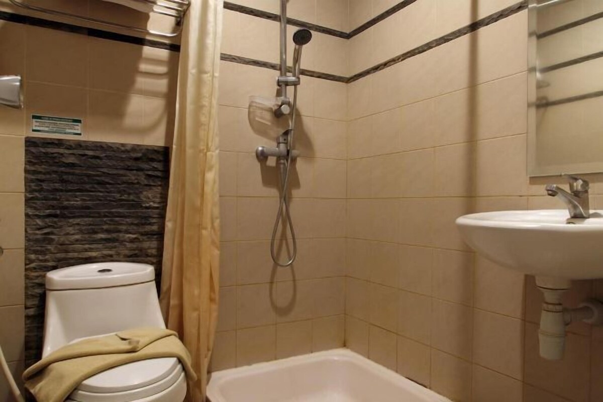 Een badkamer met douche, toilet en wastafel.