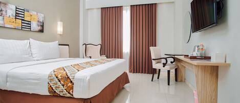 A hotel room with a bed, a desk, a chair, a television, and a window with curtains.