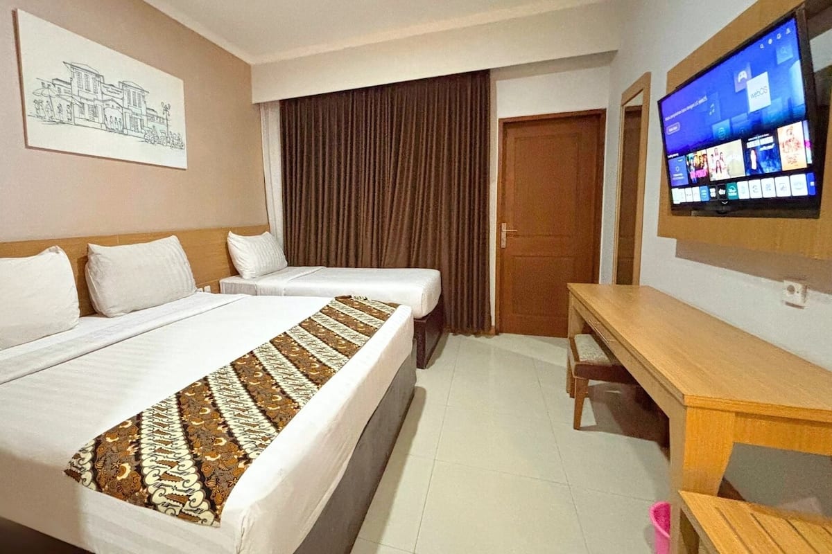 Una habitación de hotel con dos camas, un escritorio, un televisor y una puerta.