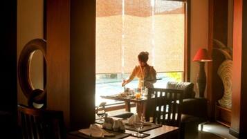 A dining area with a table set for two, a chair, and a window with a view of the outdoors.