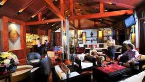 A spacious lobby with wooden beams, comfortable seating, a bar area, and a television screen. - Salana Boutique Hotel (Vientiane)