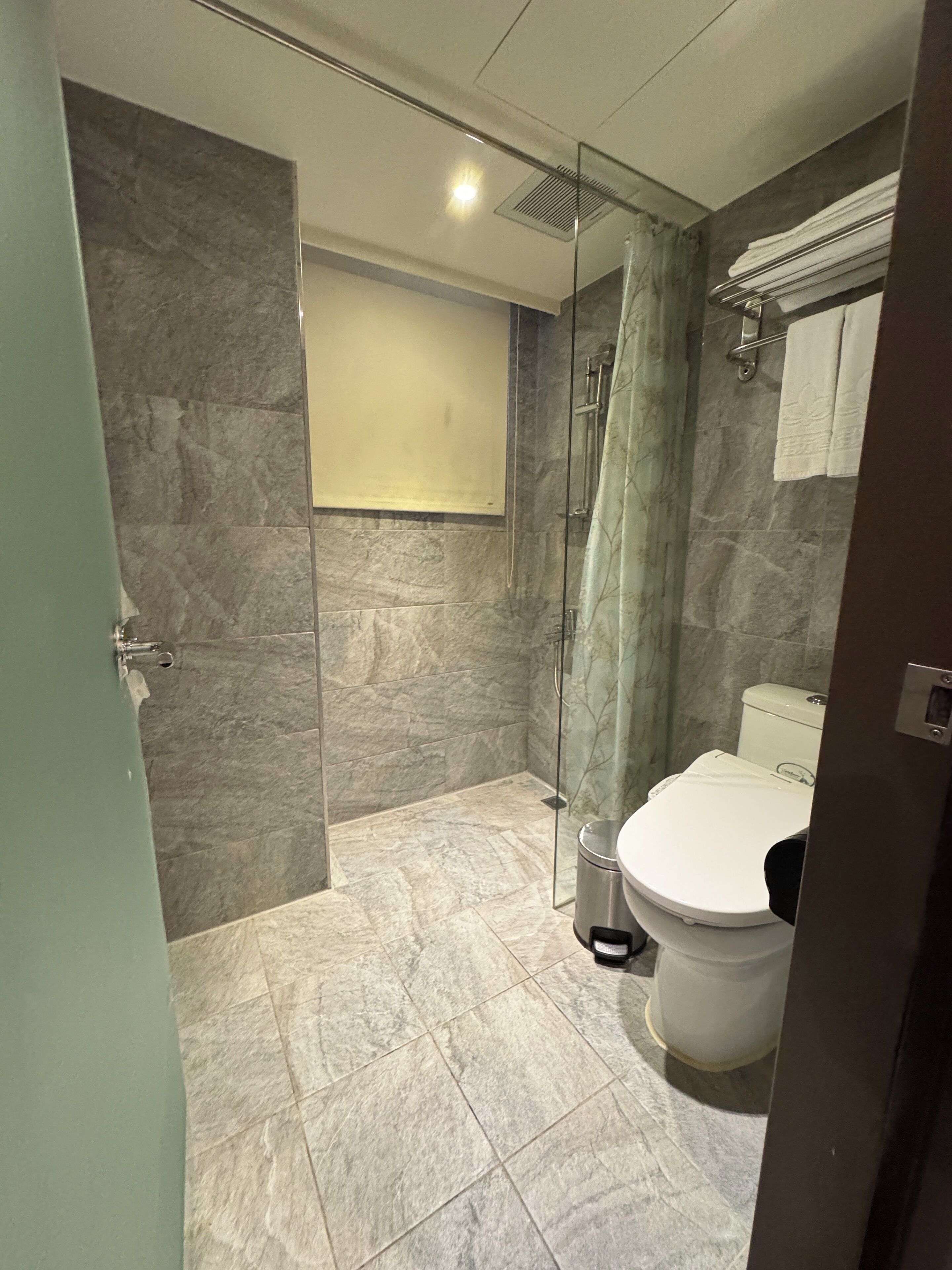 A modern bathroom with a glass-enclosed shower, a toilet, and a sink.
