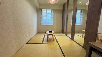 A tatami mat room with a small wooden table, a ceiling light fixture, and sliding doors.