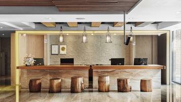 A reception area with a wooden reception desk, marble flooring, and a brick wall.