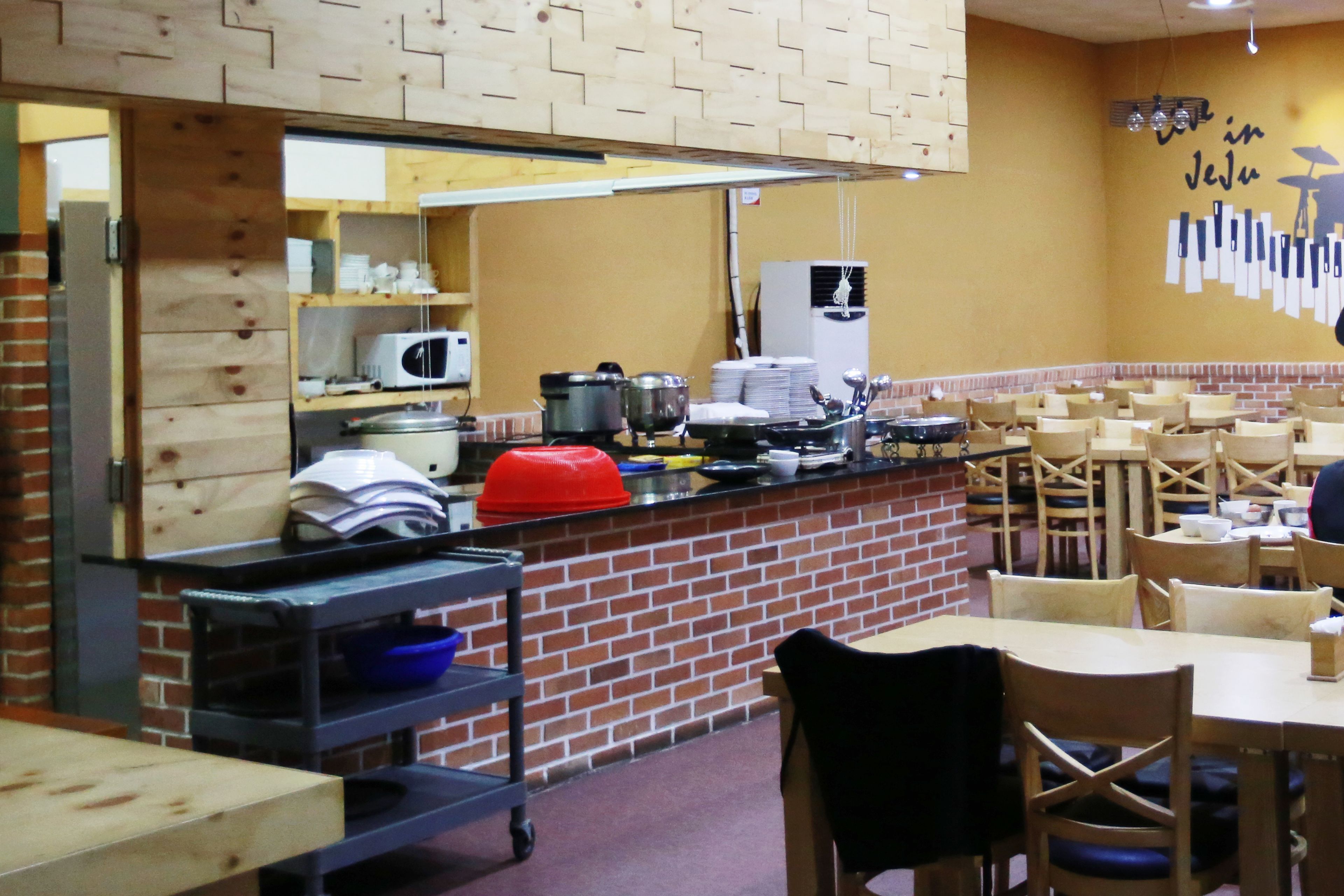 Un restaurante con pared de ladrillo, muebles de madera y una barra con equipo de cocina.
