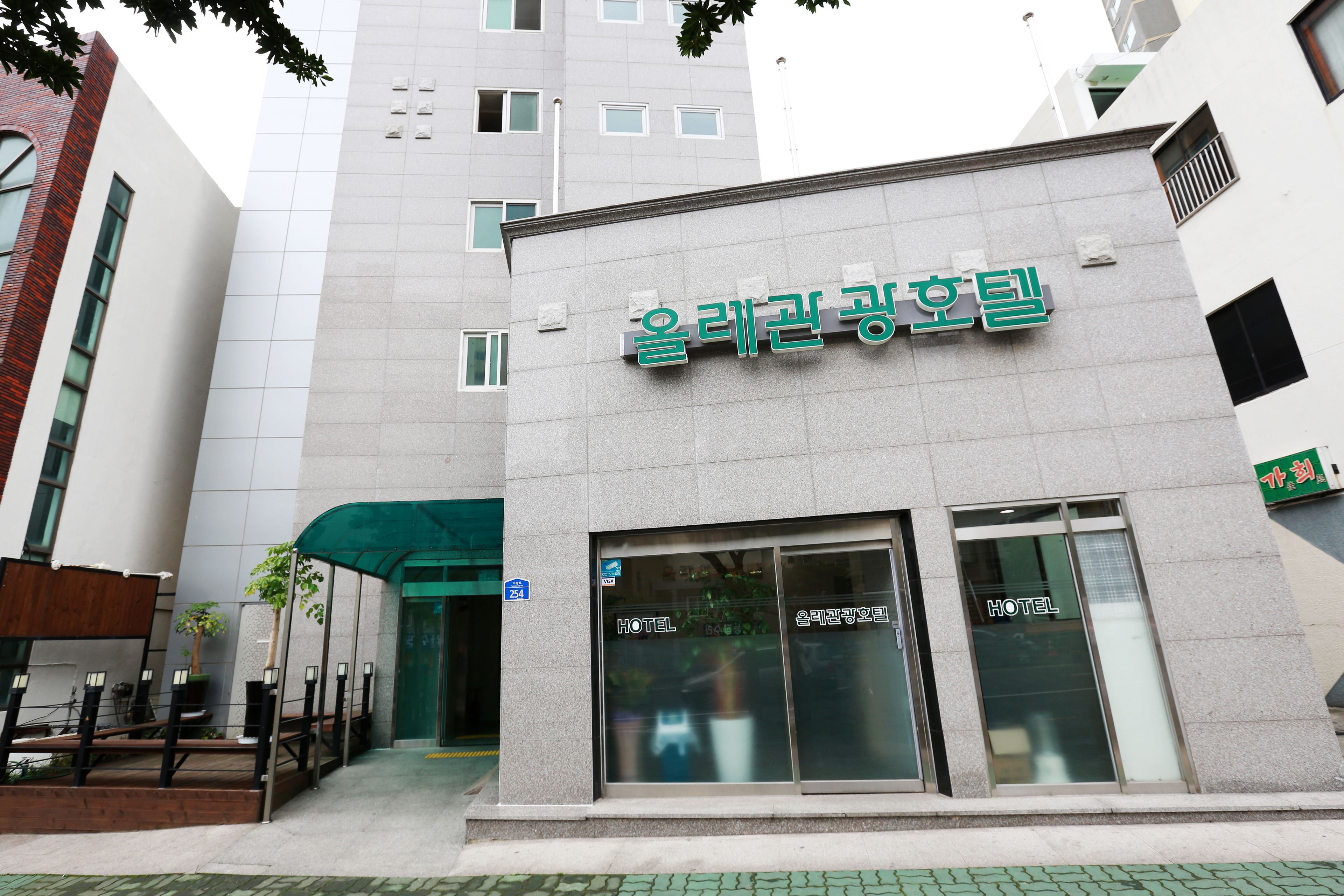 A hotel entrance with a sign reading "Hotel" and a green awning.