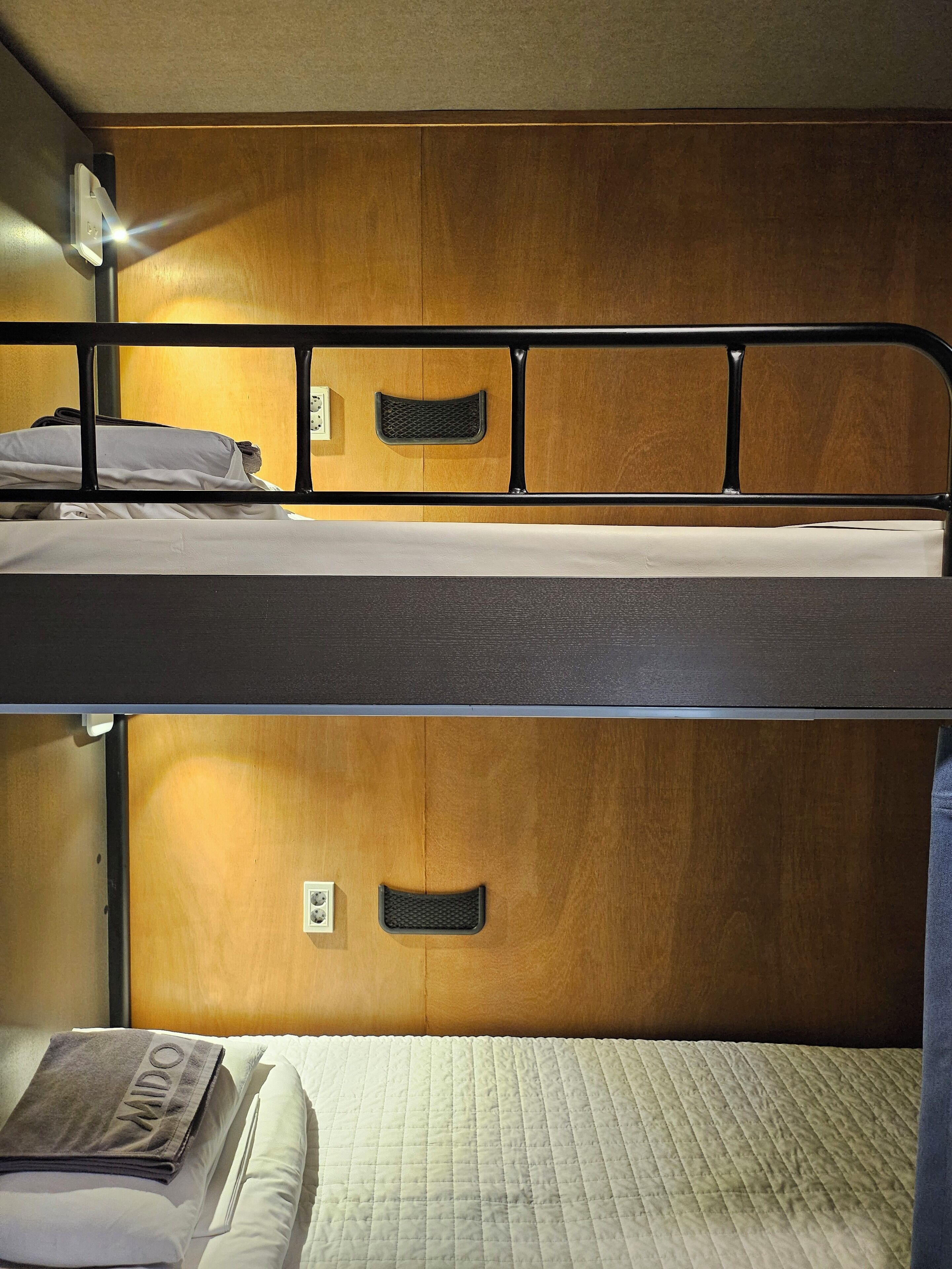 Uma cama beliche com cabeceira de madeira e uma cama inferior com colchão acolchoado.