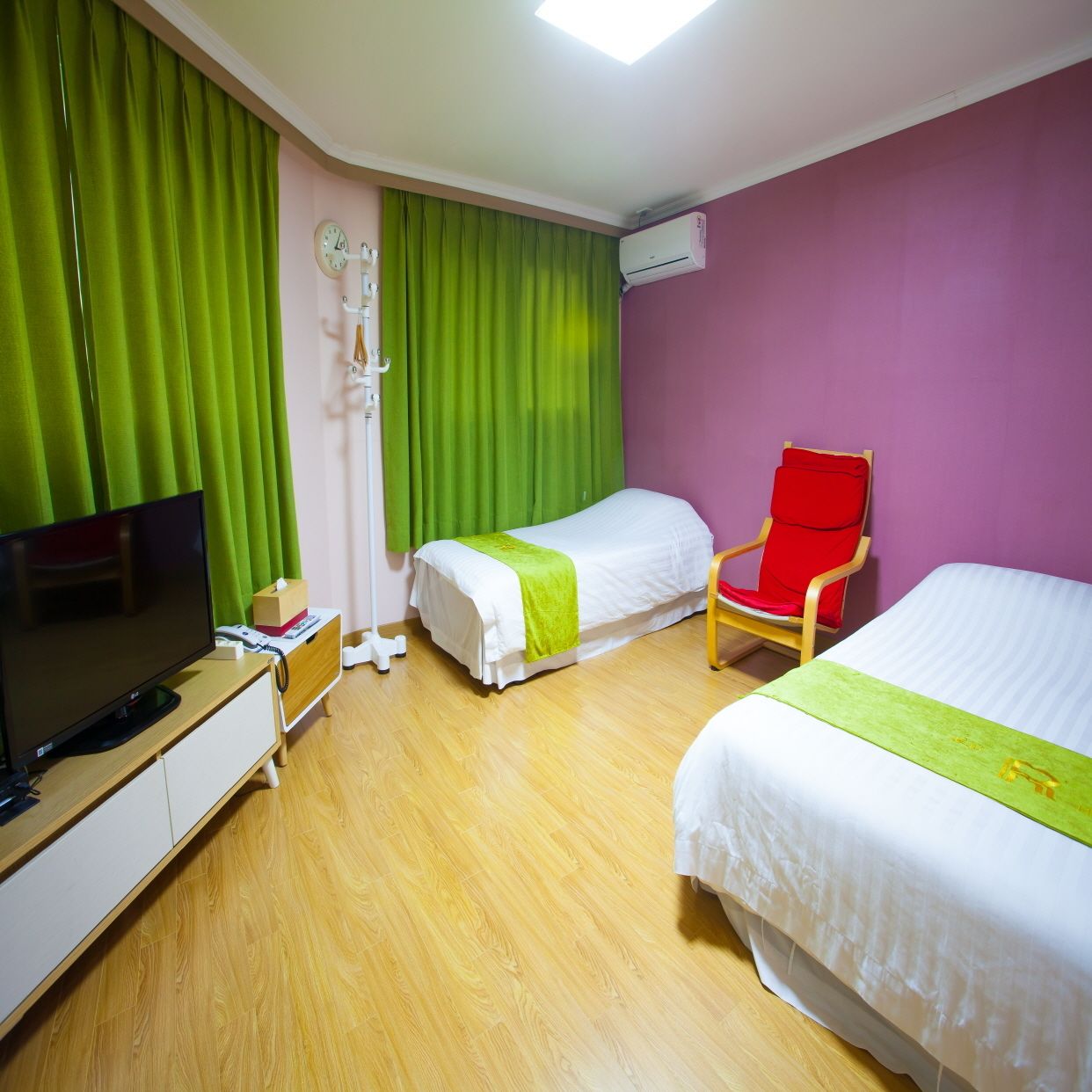 A hotel room with two beds, a TV, a chair, and a bedside table.