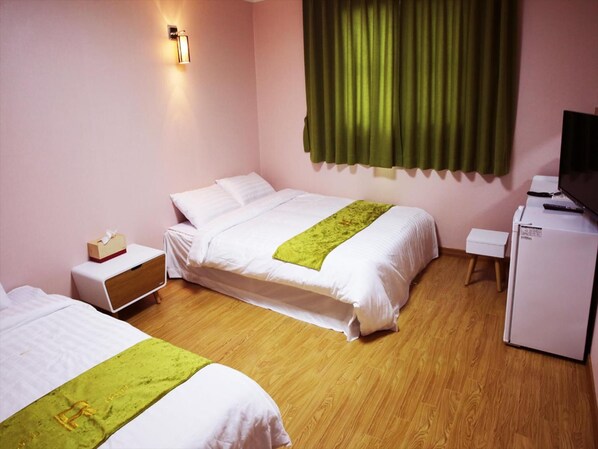 Une chambre d’hôtel avec deux lits, une petite table de chevet, un bureau avec une télévision et un réfrigérateur.