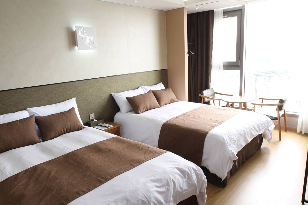 Ein Hotelzimmer mit zwei Betten, einem kleinen Tisch und einem Stuhl.