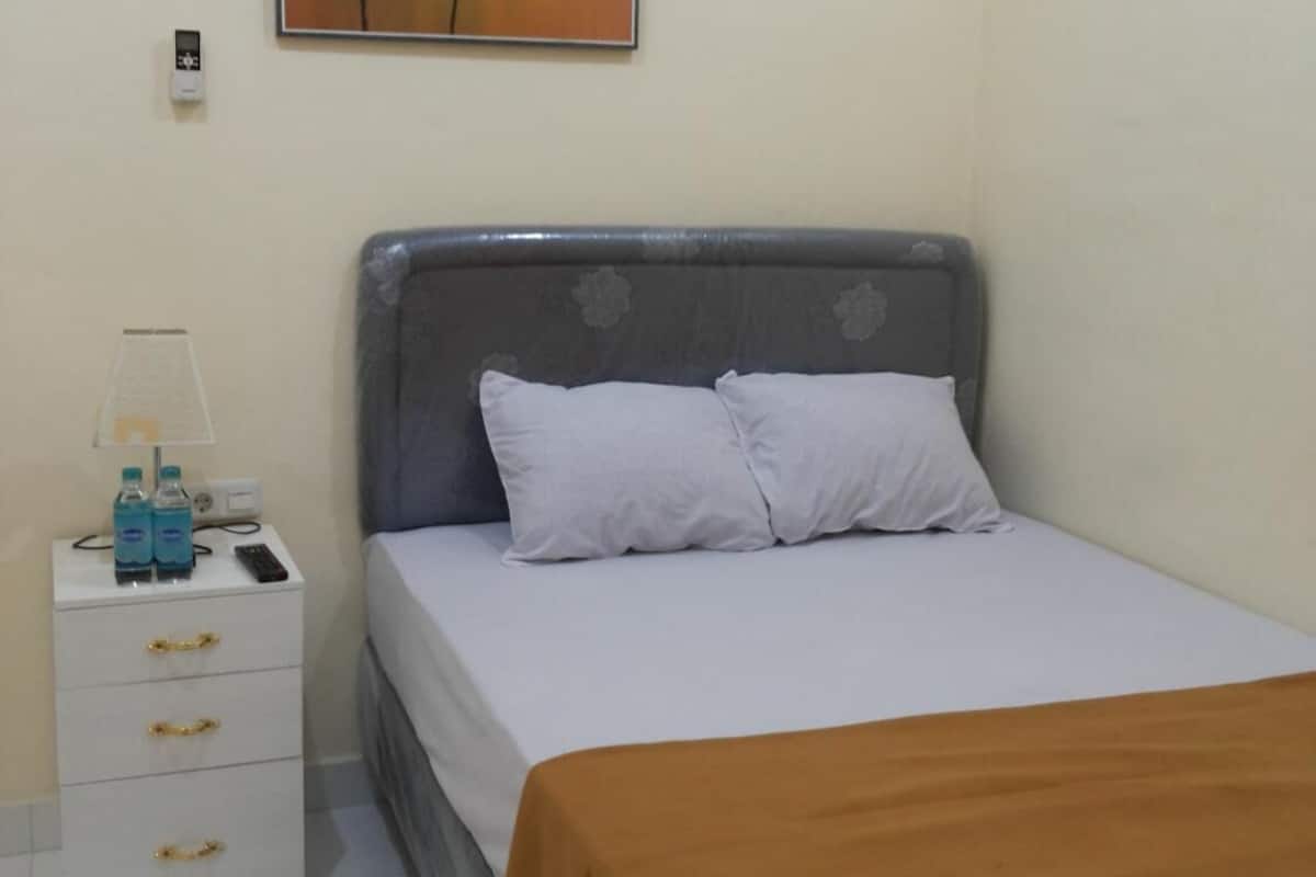 Un dormitorio con una cama, una mesita de noche con una lámpara y un cuadro en la pared.