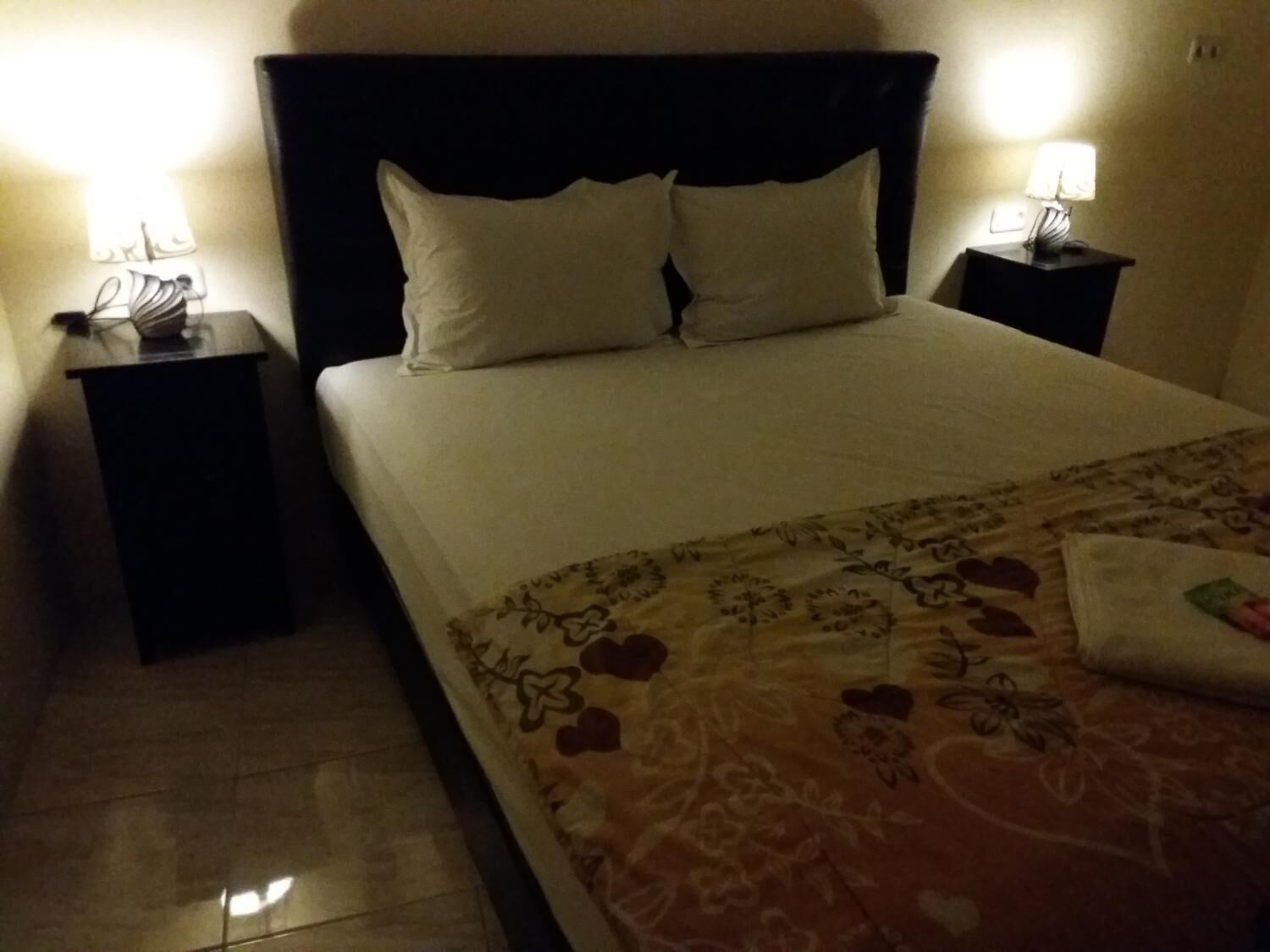 Una camera d'albergo con un letto, due comodini e una lampada da comodino su ciascun lato.