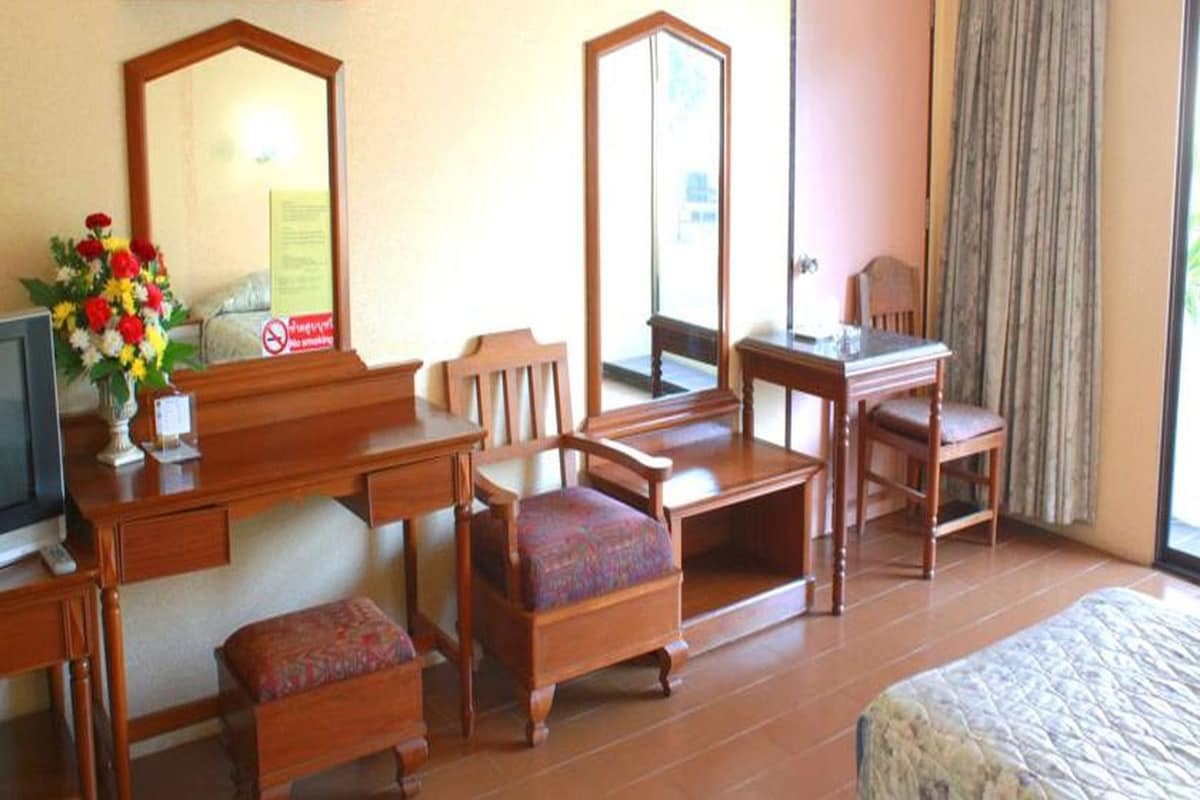 A hotel room with a bed, a desk, a chair, a sofa, a television, and a mirror.