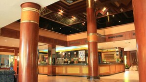 Un vestíbulo con amplias columnas de madera, un mostrador de recepción y un piso con diseño.