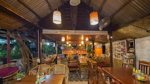 Un restaurant avec des tables et des chaises en bois, un panneau indiquant un espace détente et un tableau affichant le menu sur le mur.
