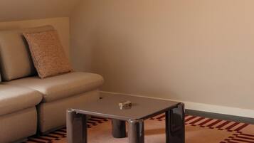 A modern living room with a sofa, a coffee table, a round mirror, and a hanging light fixture.