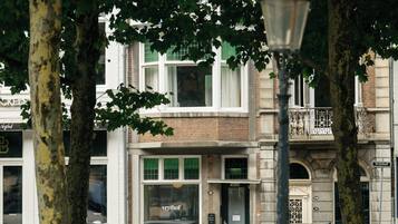 A street scene with parked cars, trees, and a building with a visible storefront.