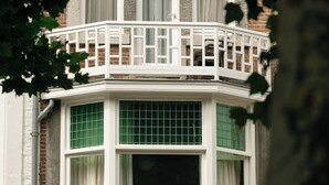 A corner building with a white balcony, multiple windows, and brick walls. -  Hotel Vrythof - just a room - digital key by email or SMS (Maastricht)