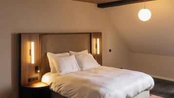 Une chambre à coucher avec un lit, une tête de lit en bois, des tables de chevet et un luminaire suspendu.