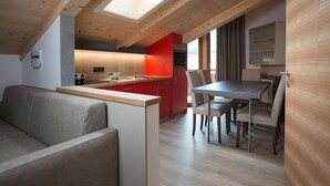 Una cocina moderna con una pared de acento roja, vigas de techo de madera y tragaluces.