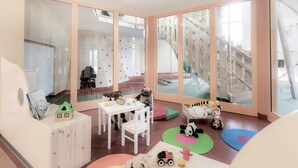 A children's playroom with climbing walls, a white table, and various toys. - JUFA Hotel Stubenbergsee (Stubenberg)