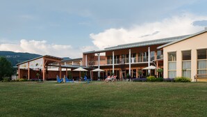 A hotel with a covered outdoor area, multiple balconies, and a grassy lawn. - JUFA Hotel Stubenbergsee (Stubenberg)