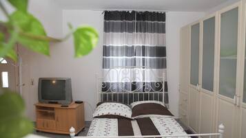 A bedroom with a bed, a TV on a wooden cabinet, and a wardrobe.