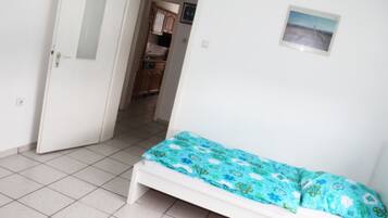 Ein Schlafzimmer mit Bett, einer Tür und Blick in eine Küche.