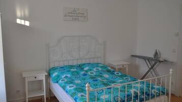 A bedroom with a bed, a nightstand, a wall-mounted ironing board, and a motivational quote on the wall.