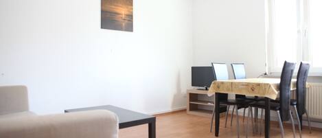 Una sala de estar moderna con una mesa de comedor, sillas, un sofá y un televisor.
